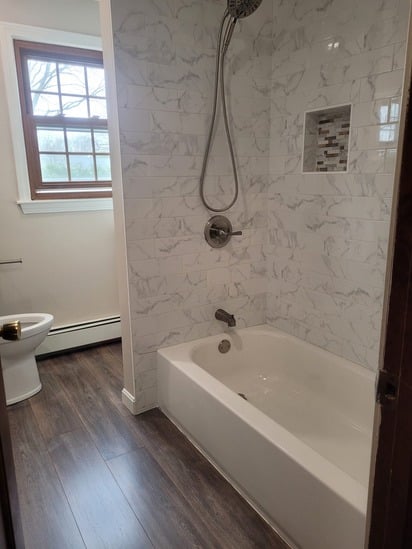 A brushed nickel rainfall showerhead and tiled niche detail in a full bath renovation.